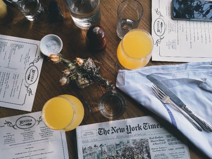 grey New York Time newspaper on table together with juice glasses