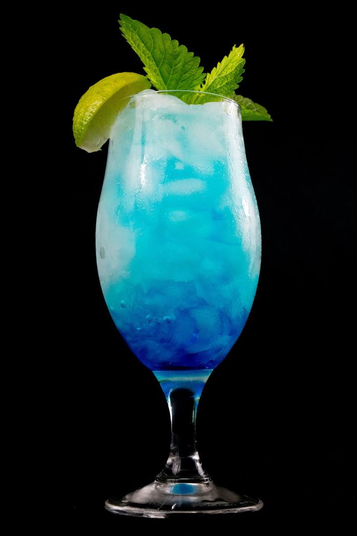 blue liquid in clear drinking glass with sliced lemon